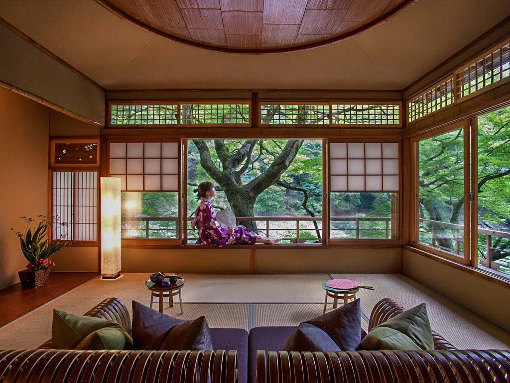 A traditional Japanese living room with wooden furniture, paper screens, and a view of nature through the windows.