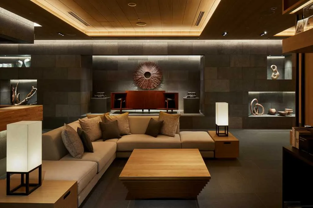 Contemporary living room with minimalist design, featuring wooden furniture, concrete walls, and metal accents.