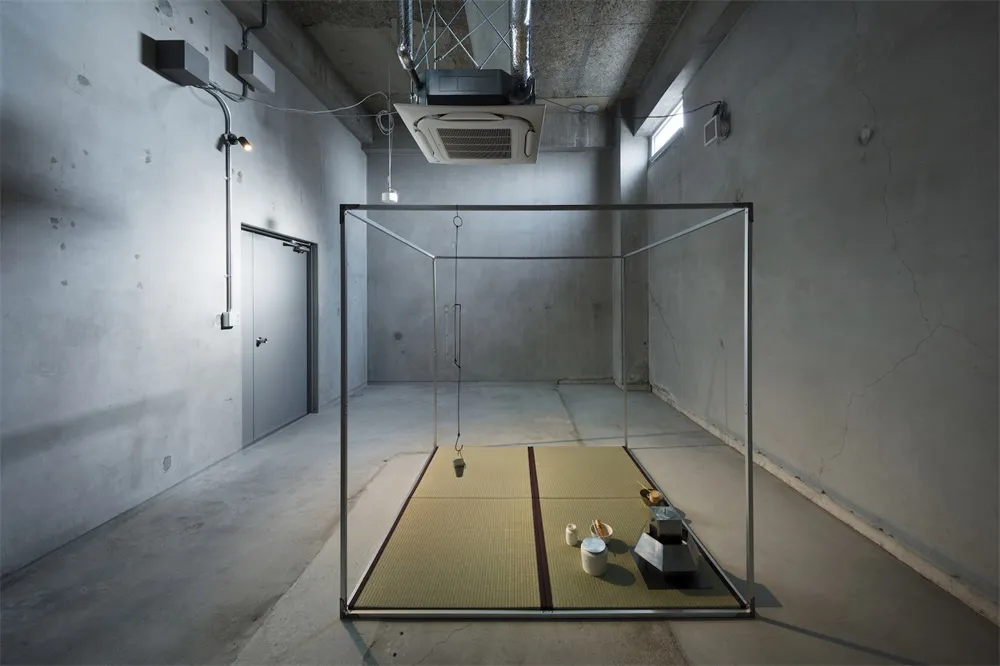 A minimalist industrial-style room with a metal-framed structure containing a tatami mat setup.