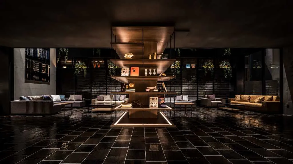 A minimalist hotel lobby with wooden shelves, glass and concrete elements.