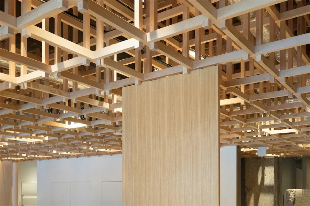 A modern interior space featuring a wooden grid ceiling and column.