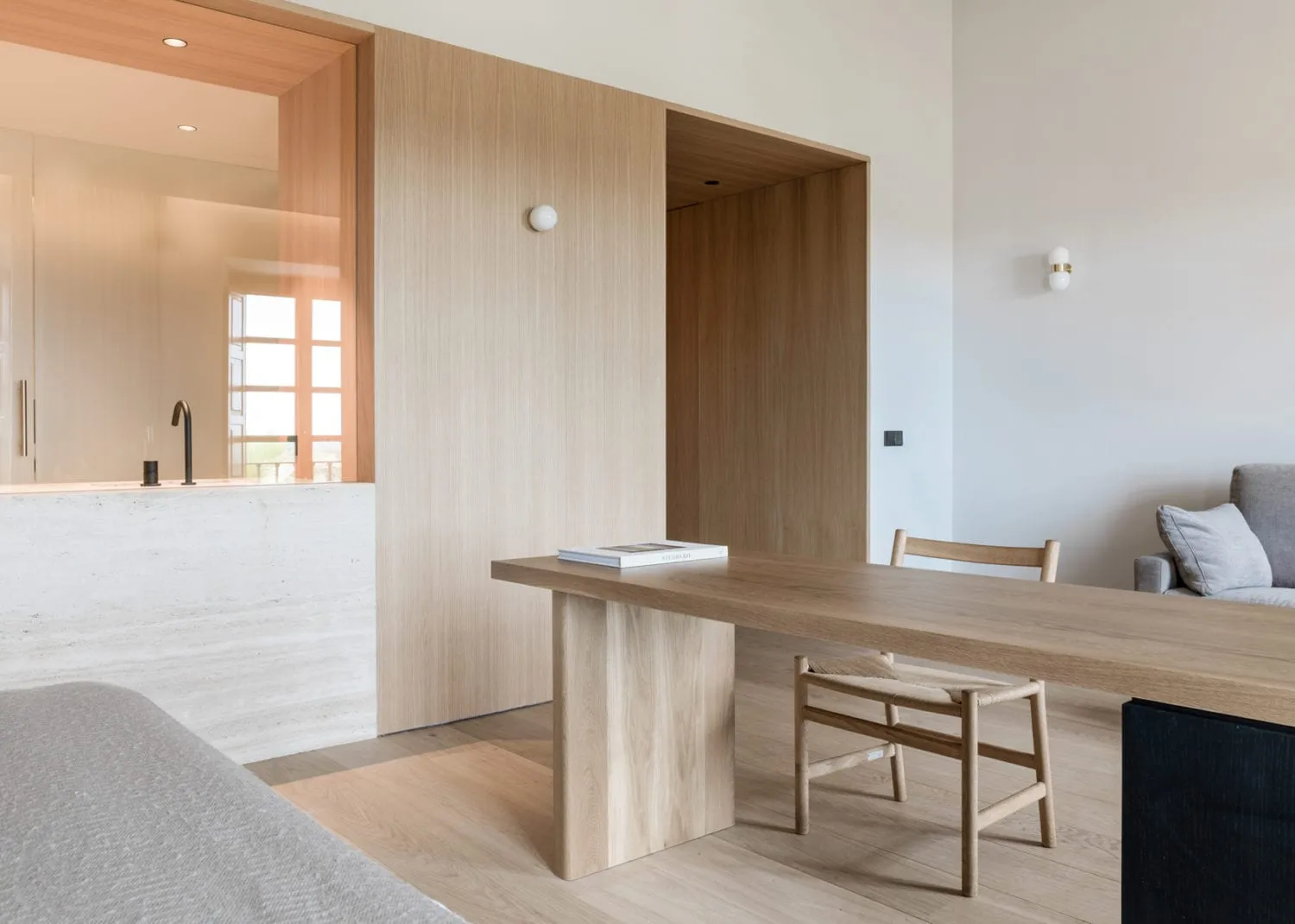 A modern living room with a wooden bench, chairs, and table.
