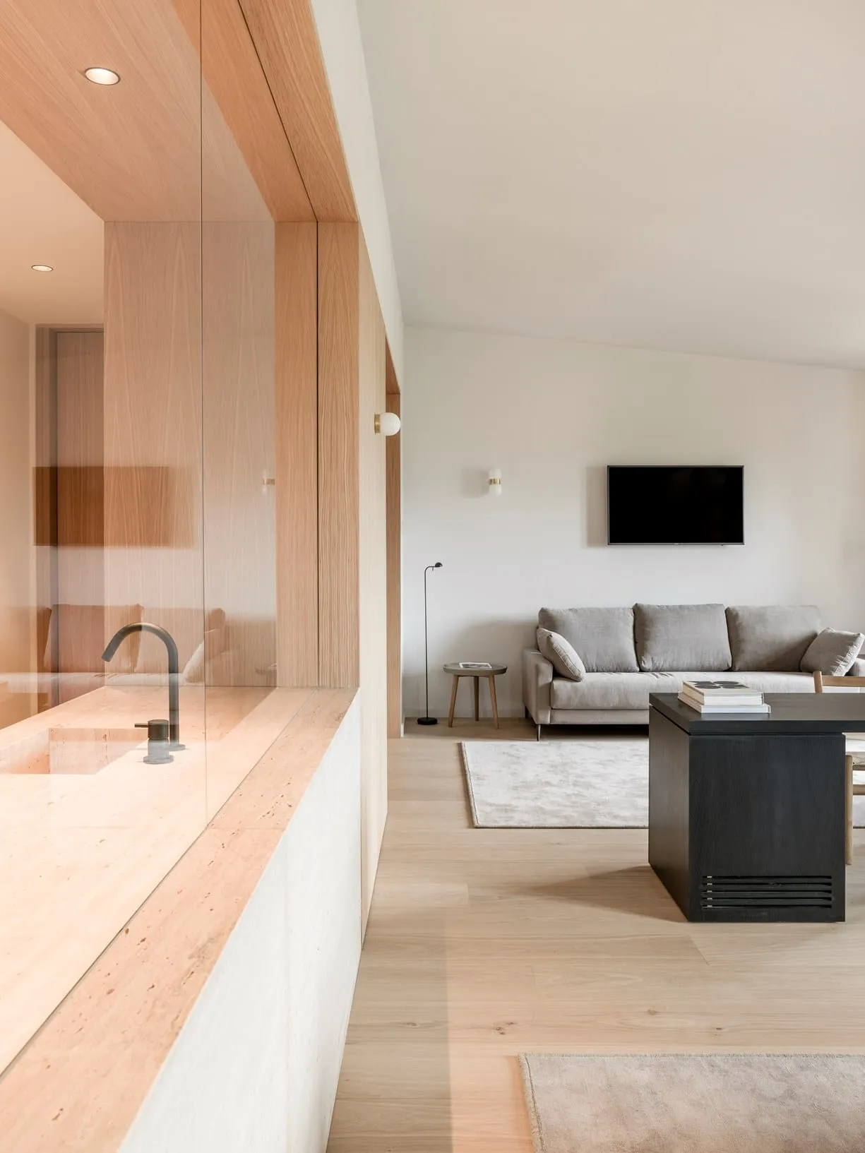 A modern living room with wood flooring, a sofa, a coffee table, and a flat-screen TV.