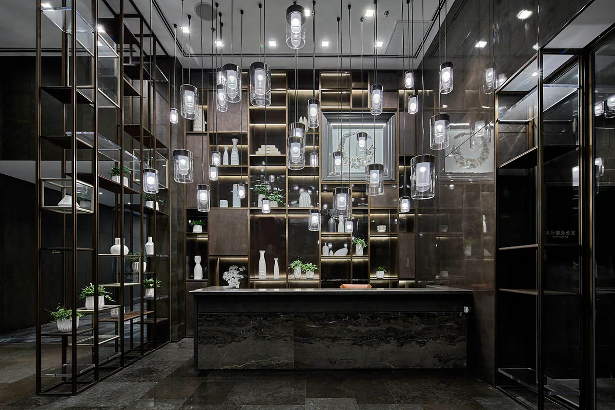 A modern reception desk made of glass and marble, featuring hanging pendant lights and a spacious counter.