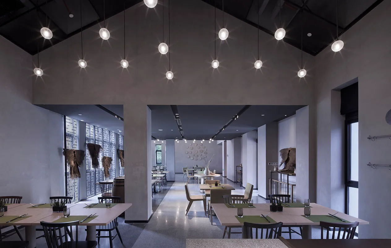 A modern restaurant interior with concrete walls and hanging lights.