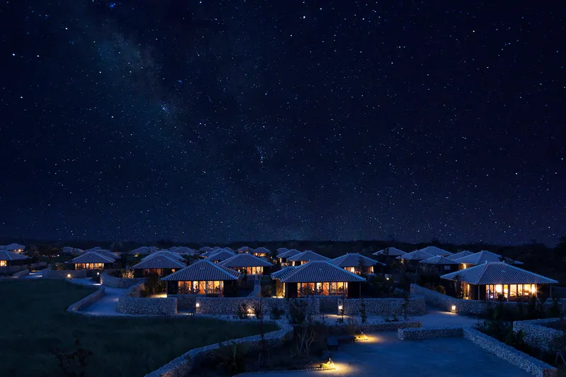 A serene night view of residential buildings with stone walls and glass windows.