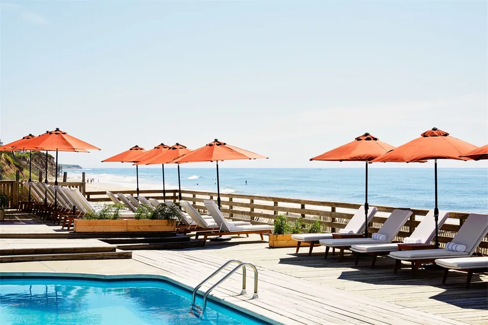 Vacation resort with wooden decks, lounge chairs, and umbrellas overlooking the ocean.
