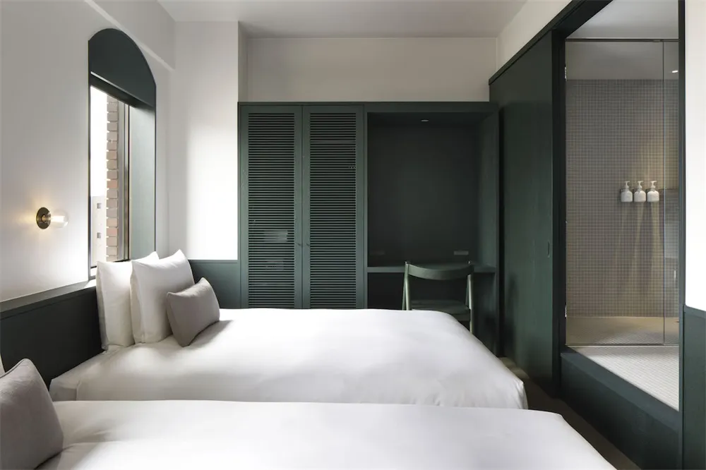 A modern bedroom featuring two beds with white bedding and a minimalist design.