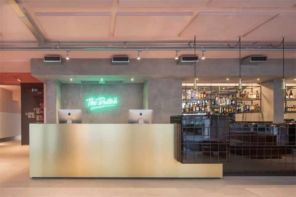 Modern design bar counter featuring a concrete finish, with a neon sign that says 'The Dutch'.