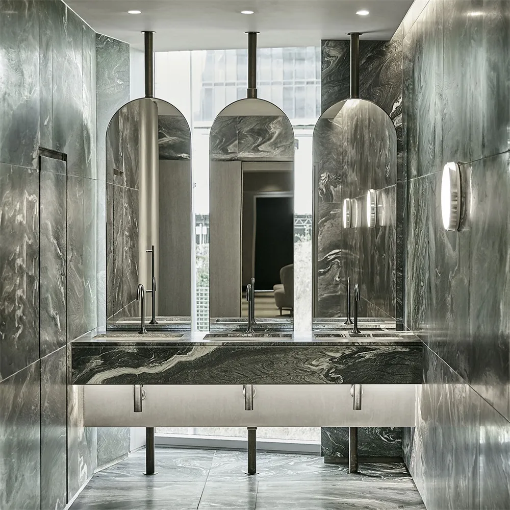 A modern marble bathroom with sleek, curved mirrors and elegant fixtures.