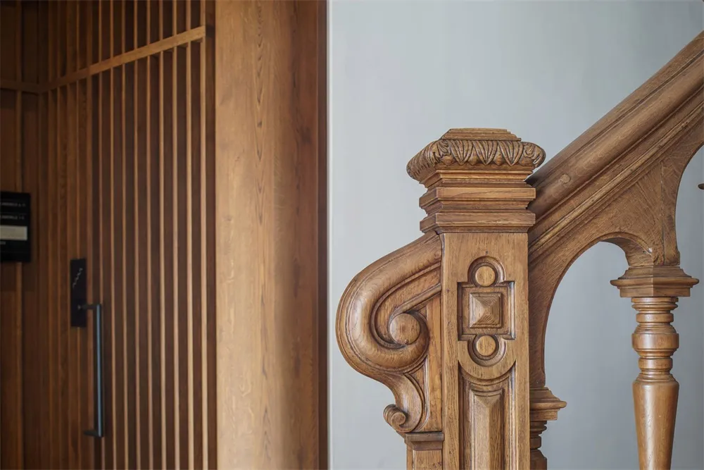 A detailed wooden staircase with ornate carvings and a wooden wall.