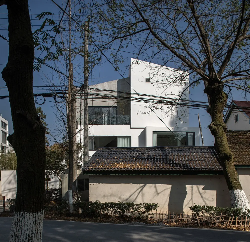 一棟擁有白色混凝土外牆與大型窗戶的現代住宅。
