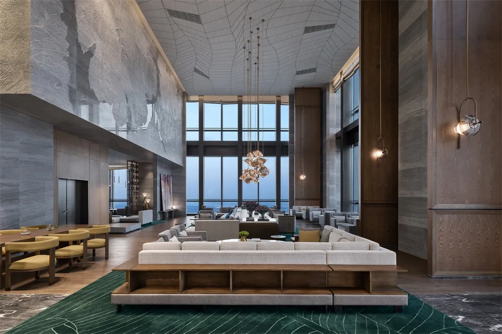 A modern hotel lobby featuring a combination blend of materials and design elements, with a large sofa, chandelier, and floor