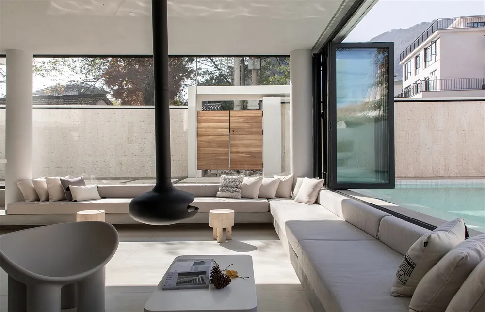 Modern minimalist residential space featuring concrete and glass materials, with open-plan layout and large windows.
