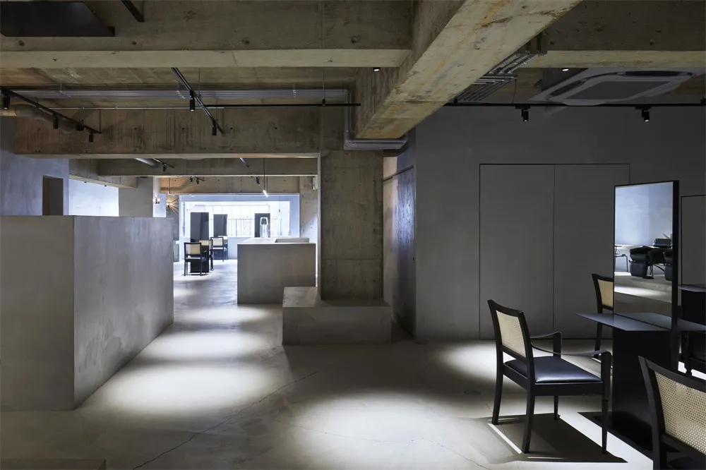 A spacious, industrial-style office interior with concrete walls, concrete cubes, and concrete countertops. The space feature