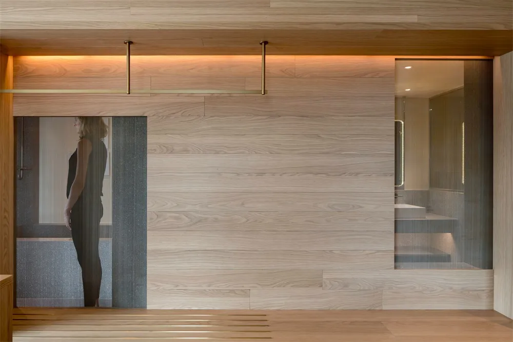 Modern bathroom featuring wooden walls and a glass partition.