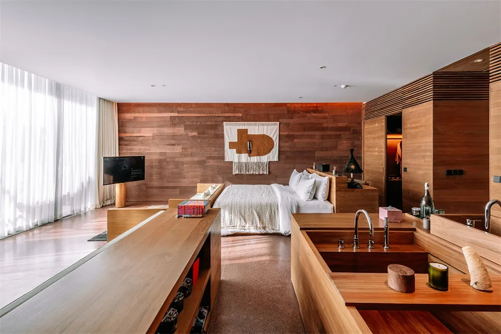 A modern bedroom with a wooden wall, white bedding, and a minimalist design.