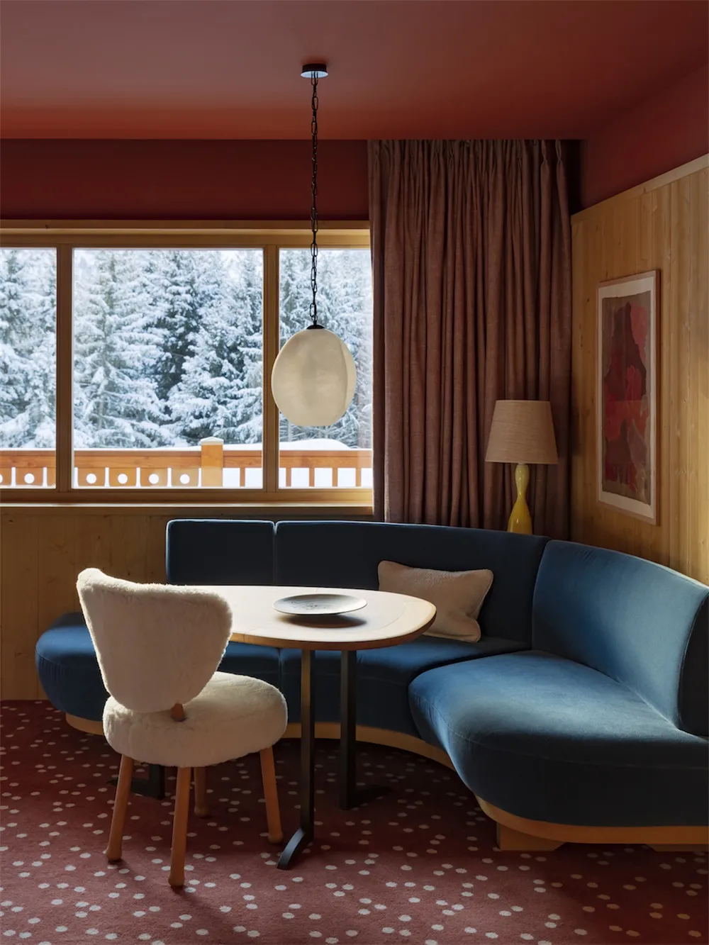 Modern interior design room featuring a blue velvet sofa, wooden floor, and a white furry chair.