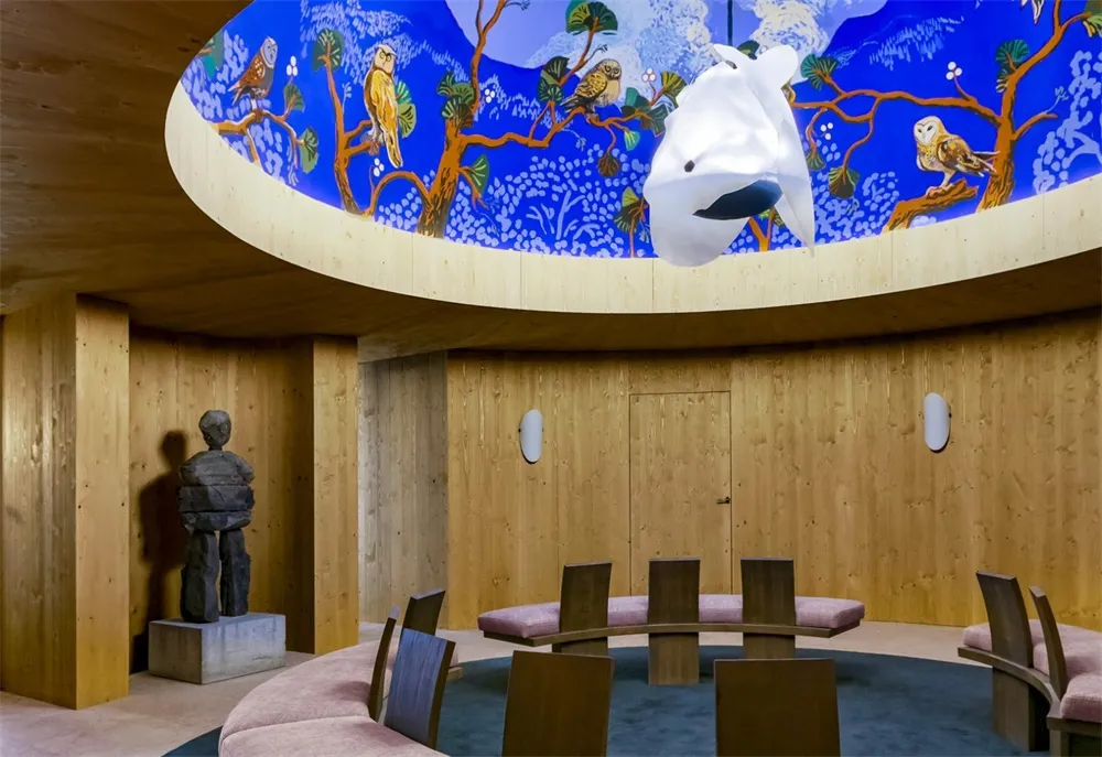 當代室內空間,木質牆面搭配圓形餐桌,以及帶有鳥類主題壁畫的圓形窗戶。
