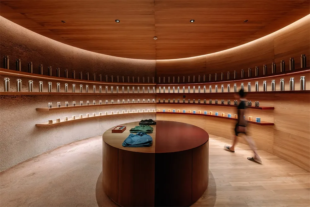 A modern retail shop with a wooden round counter and shelves filled with bottles.