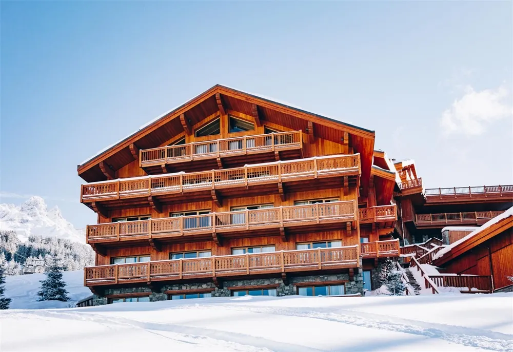 Front view of a multi-story wooden chalet hotel with snowy landscape.
