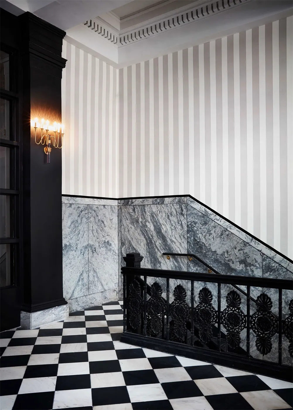 A black and white marble staircase interior with striped wallpaper.