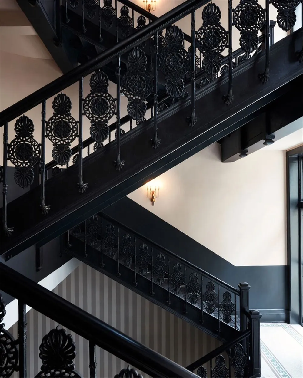 A grand black iron staircase with ornate railings and lighting in an interior setting.