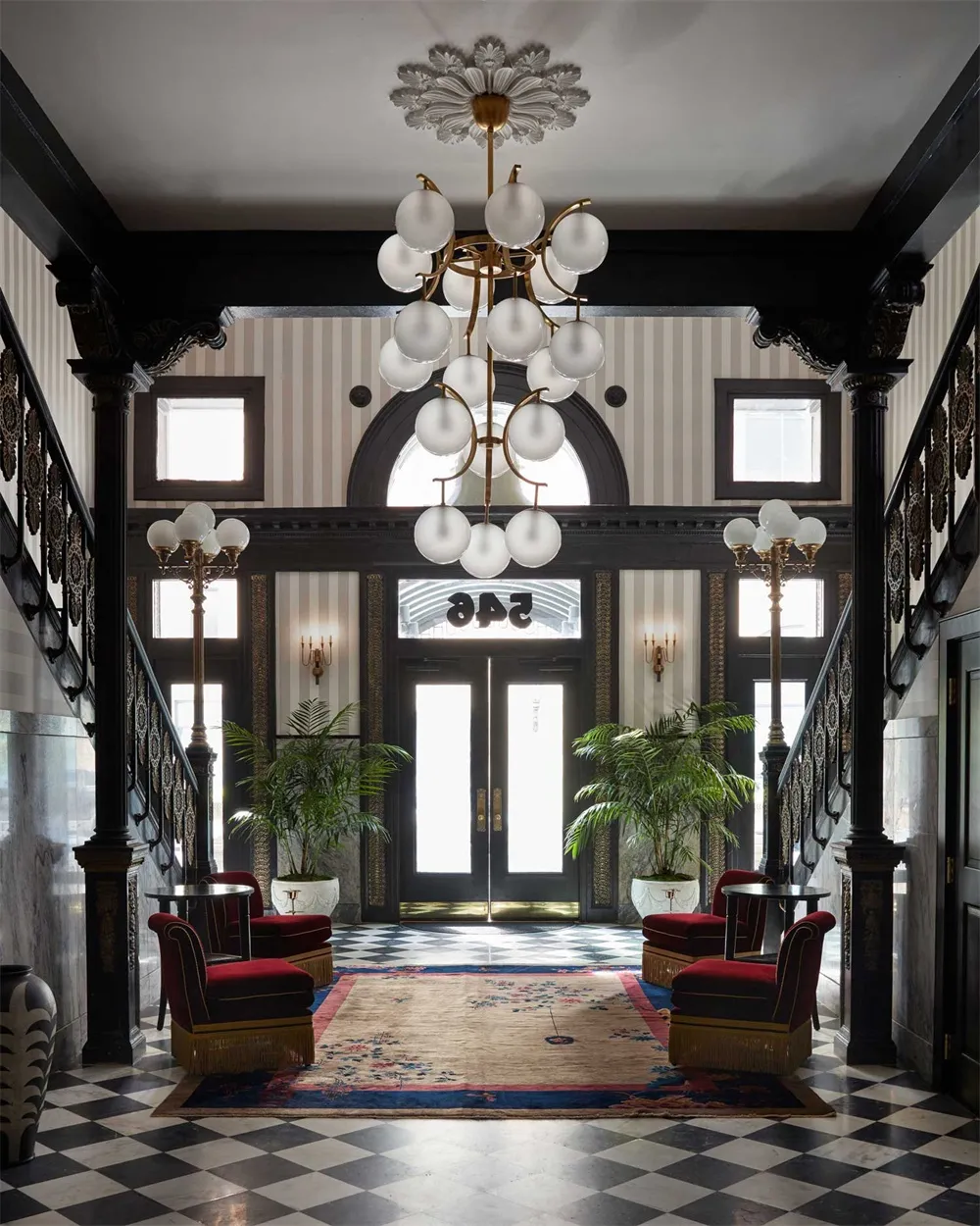 Classical-style lobby featuring marble columns, glass chandelier, and carpet flooring.
