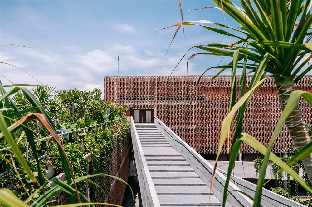 A modern building with stairs leading to the entrance, featuring wood construction.