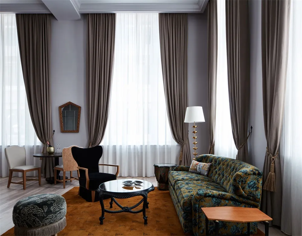 Modern living room with dark wooden floor, plush seating area, and large windows with sheer curtains.