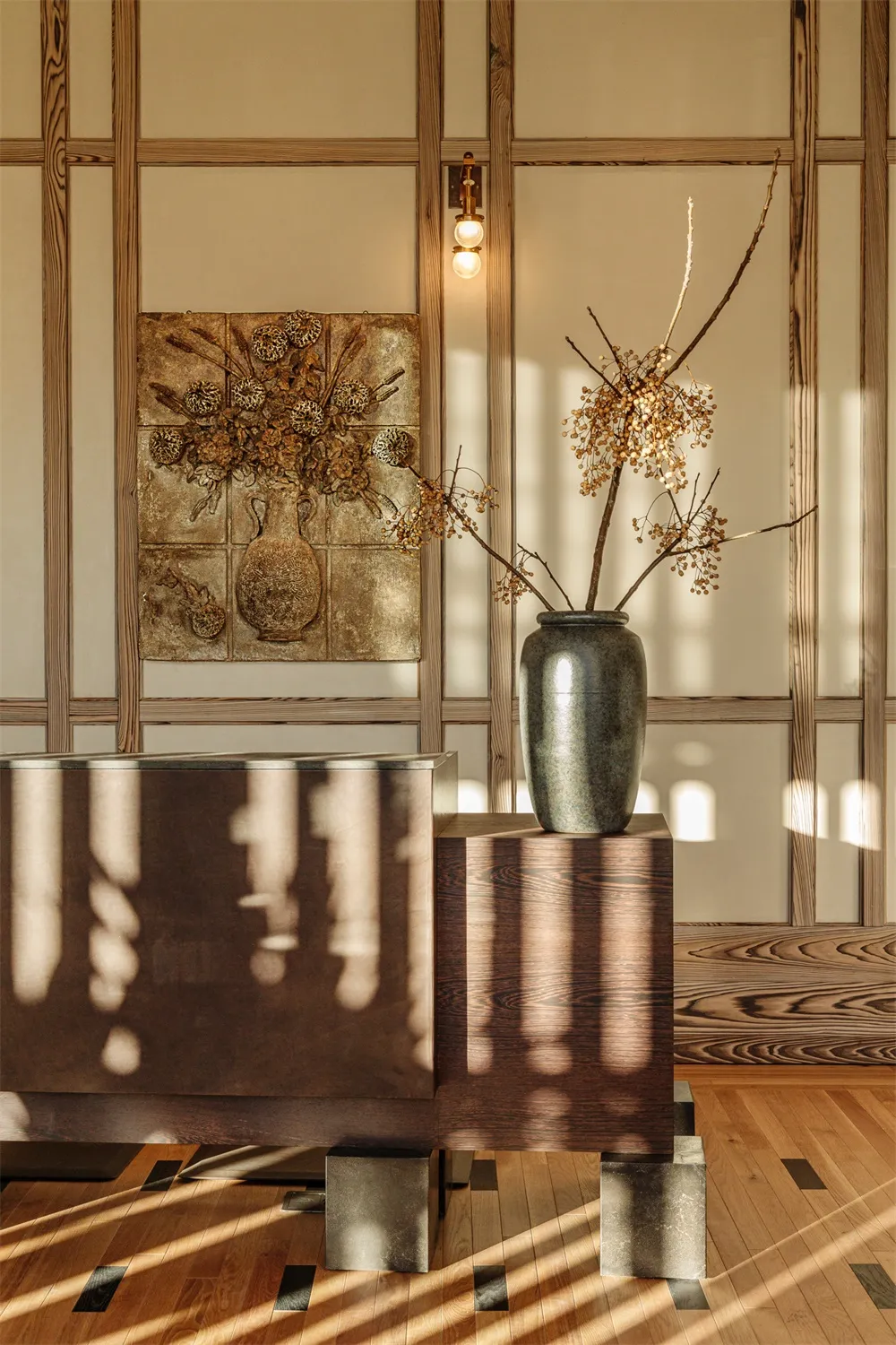 Modern living room with wooden paneling, a vase with dried flowers, and a painting of a vase with dried flowers.