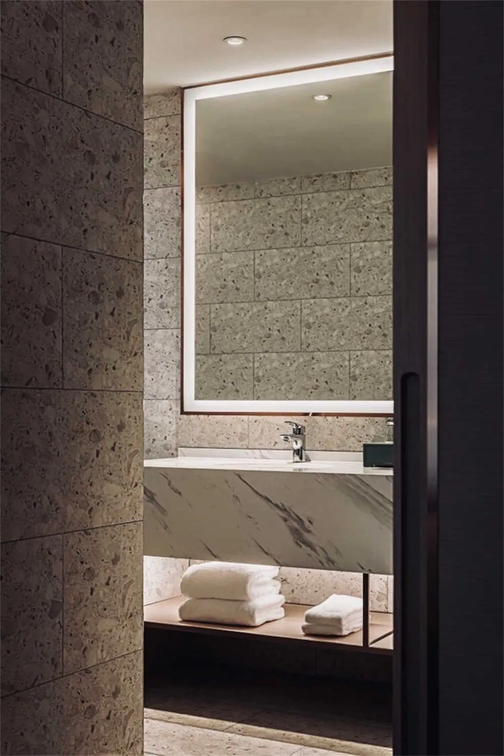 Modern bathroom with marble fixtures and a large mirror.