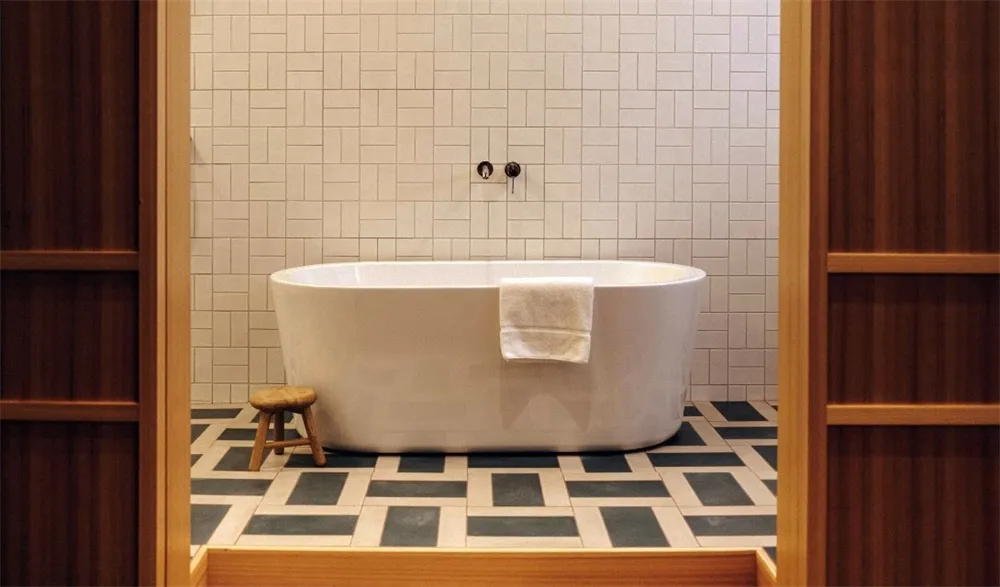 Modern bathroom featuring a sleek white freestanding tub with a white towel draped over the side, set against a background of
