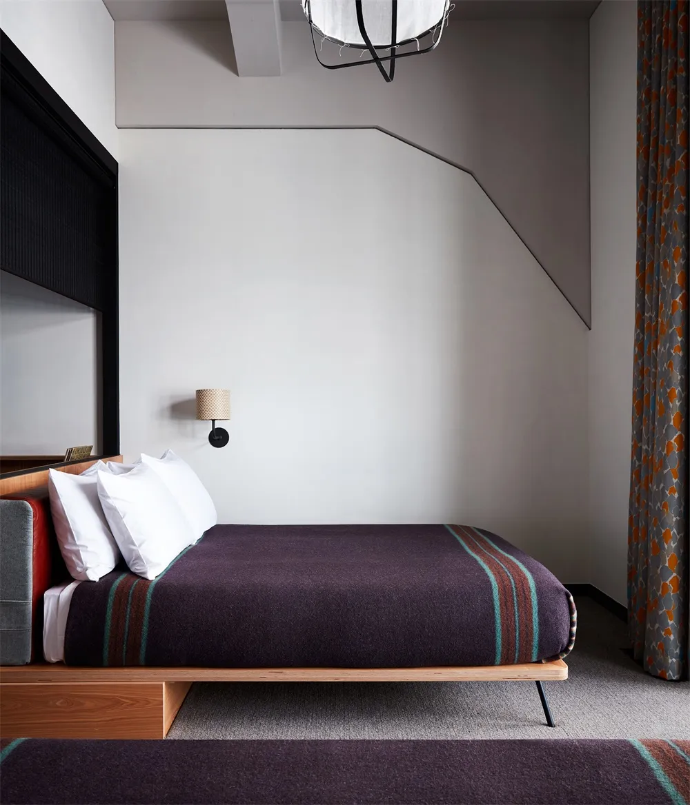 A minimalist bedroom features a comfortable bed covered with a textured, patterned blanket.