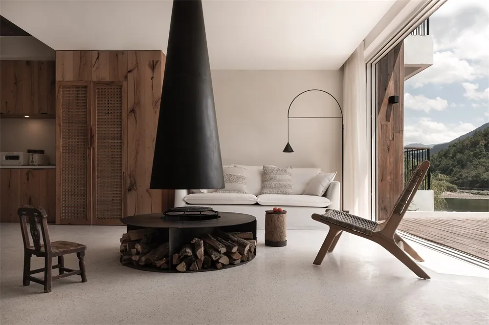 A minimalist living room with concrete walls and floors, featuring a modern fireplace and lounge furniture.