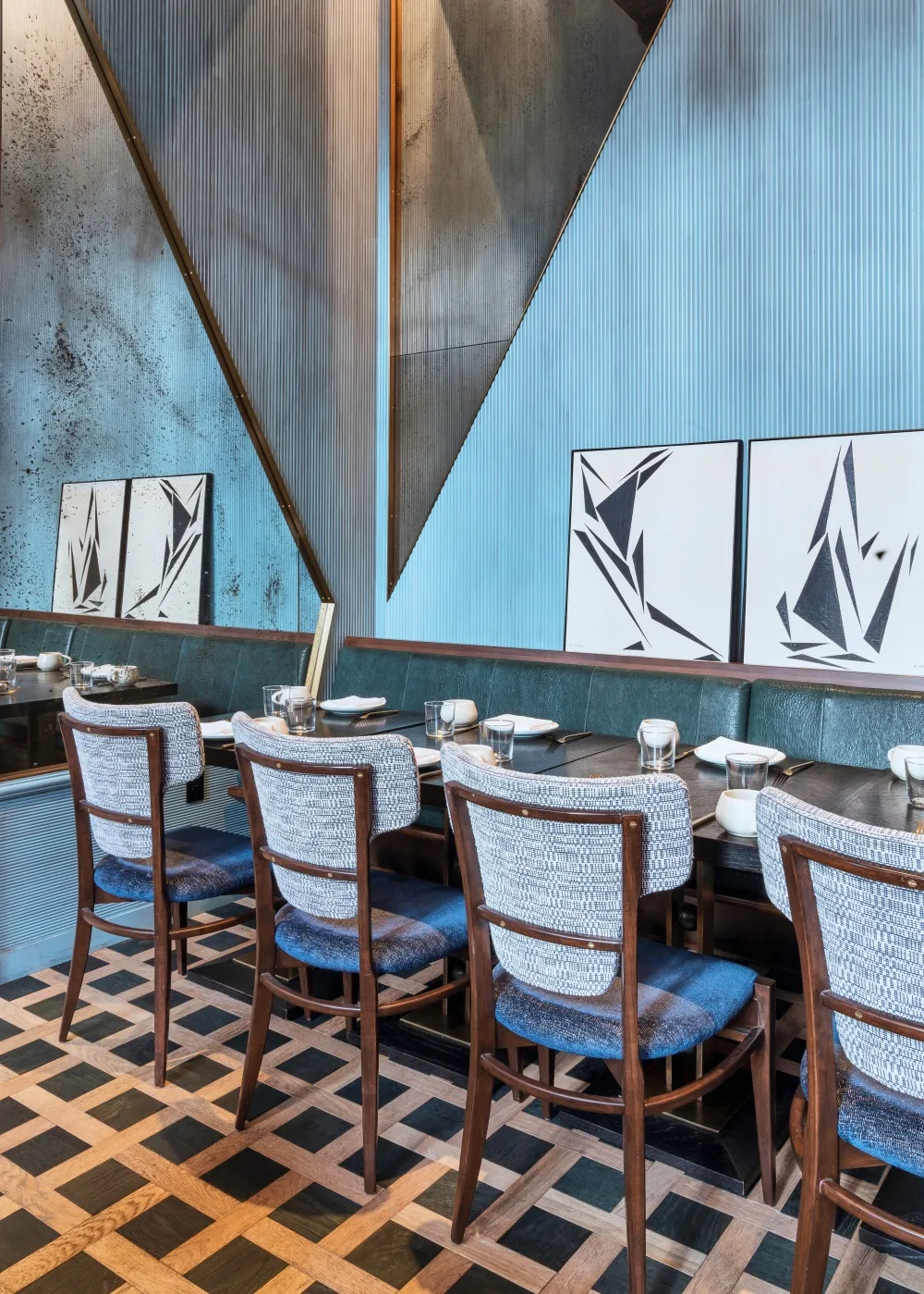 Modern restaurant interior with wooden flooring, metallic chairs, and plaster walls