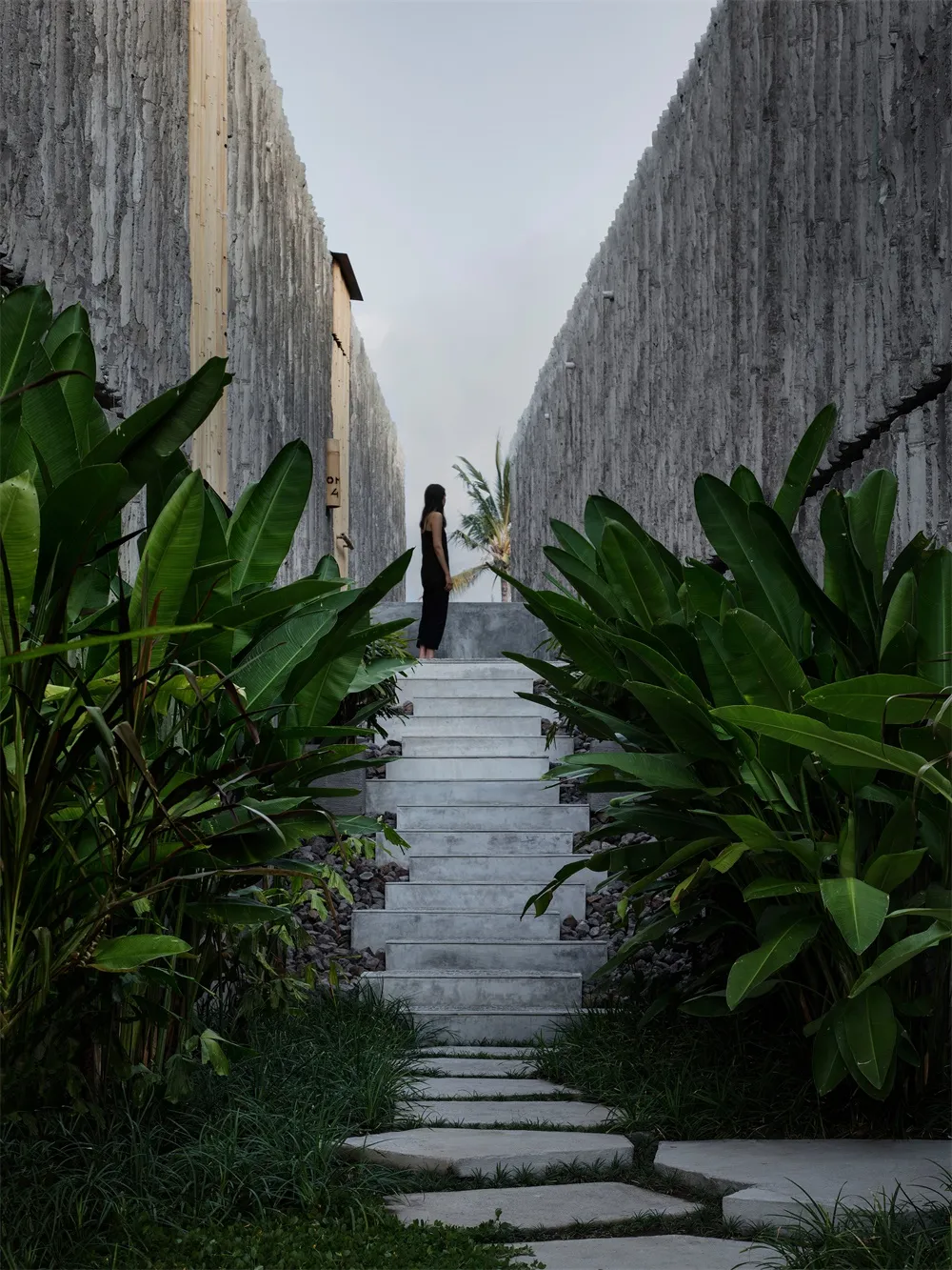 A minimalist landscape featuring a concrete pathway bordered by lush greenery.