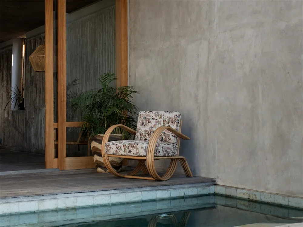A minimalist armchair with floral upholstery near a poolside area.