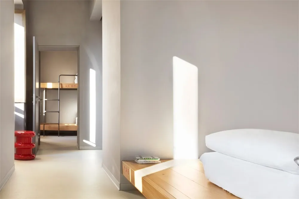 Modern minimalist bedroom with white furniture and wooden accents, featuring clean lines and an open floor plan.