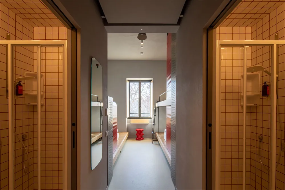 A modern, industrial-style hostel room featuring tiled walls and concrete bunk beds.