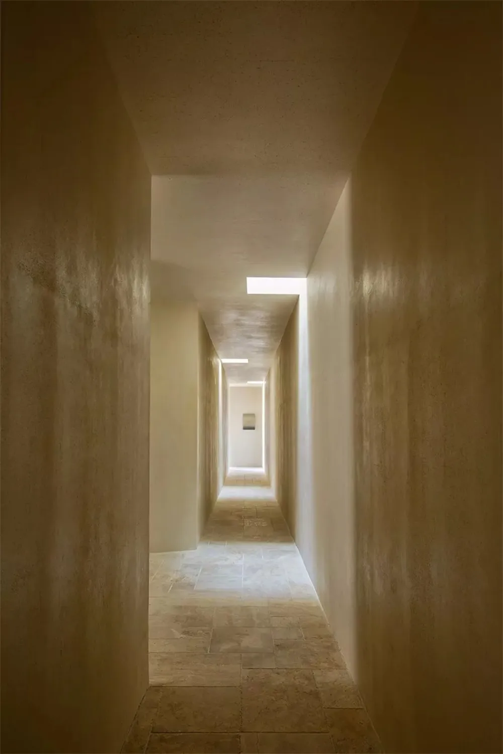 A minimalist corridor with concrete walls and a skylight.