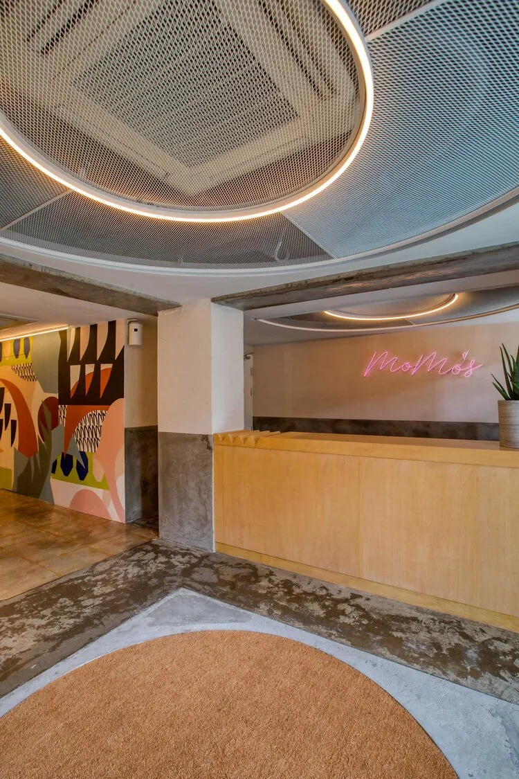 A minimalist reception desk made of wood and concrete, featuring a circular light fixture above it.