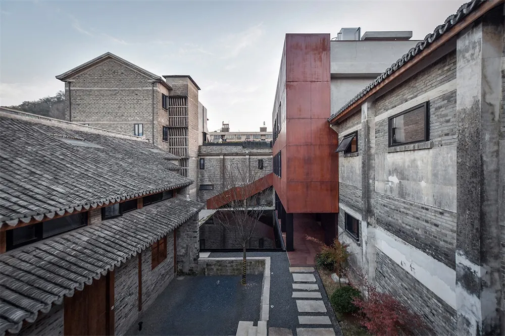 A modern residential pavilion with brick and concrete walls, featuring a courtyard and pathway.