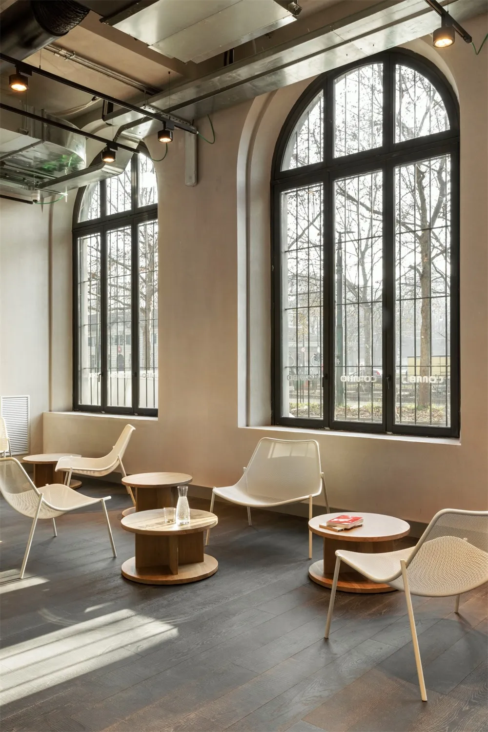 Modern minimalist coffee shop interior with wooden furniture and large windows.