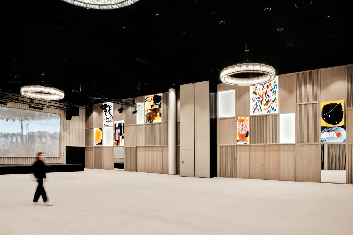 A spacious, modern conference hall with wooden paneling and glass walls.