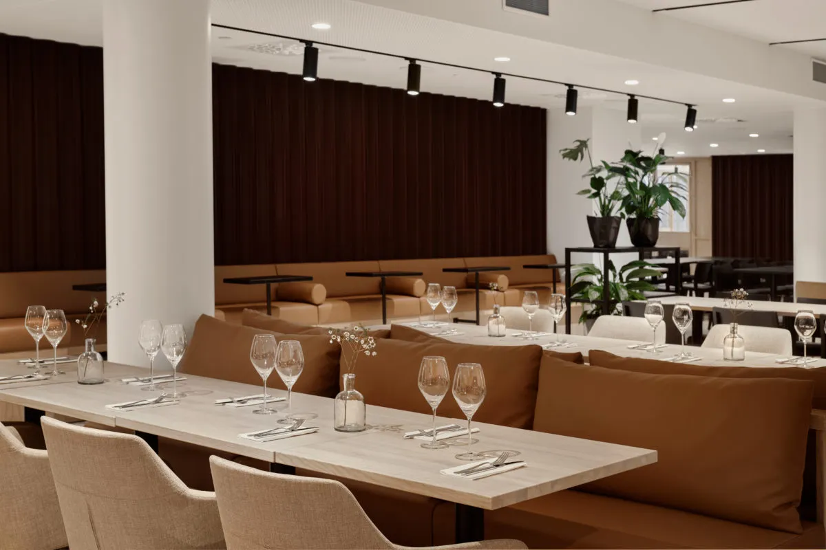 A modern restaurant interior featuring brown leather cushions and neutral furniture.