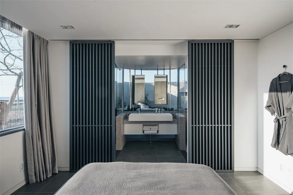 A modern bedroom featuring concrete and glass materials.