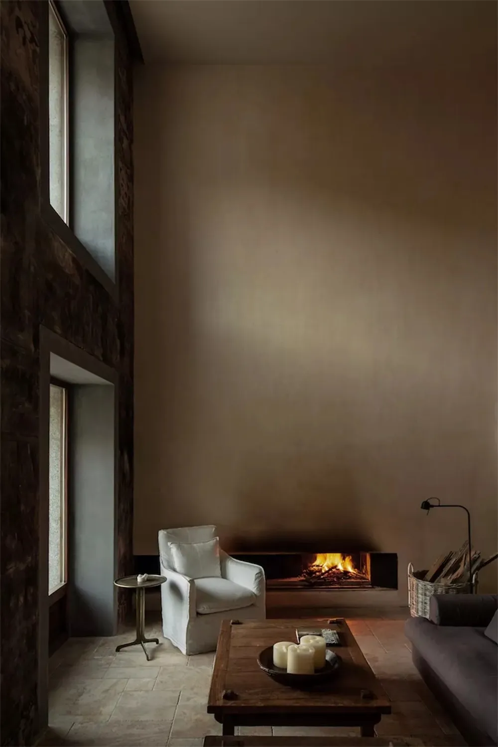 Minimalist living room featuring a stone, wood, and concrete design scheme with a fireplace, sofa, and coffee table.