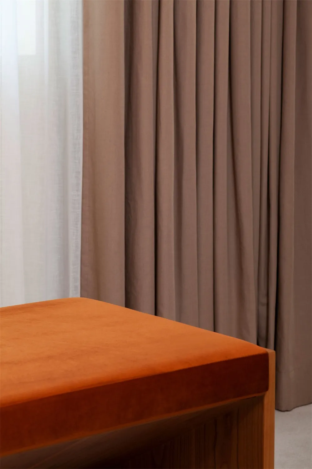 A close-up view of modern, soft orange curtains drawn tightly across a window.