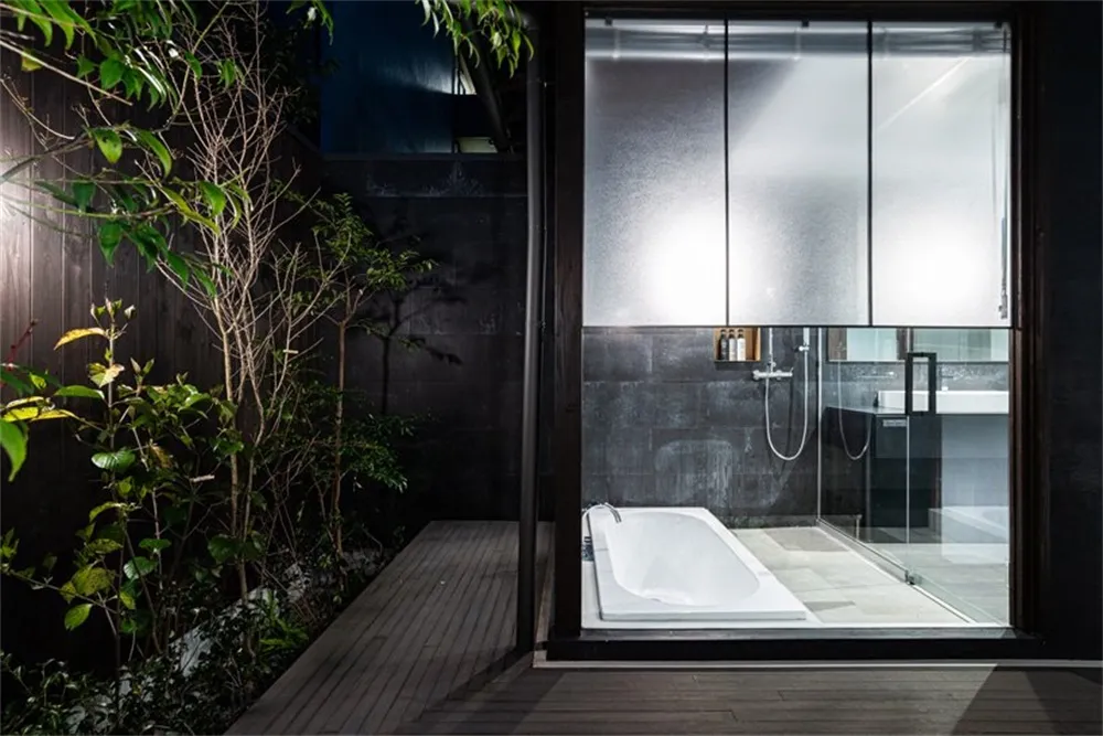 A modern minimalist bathroom with concrete walls and a glass door shower.